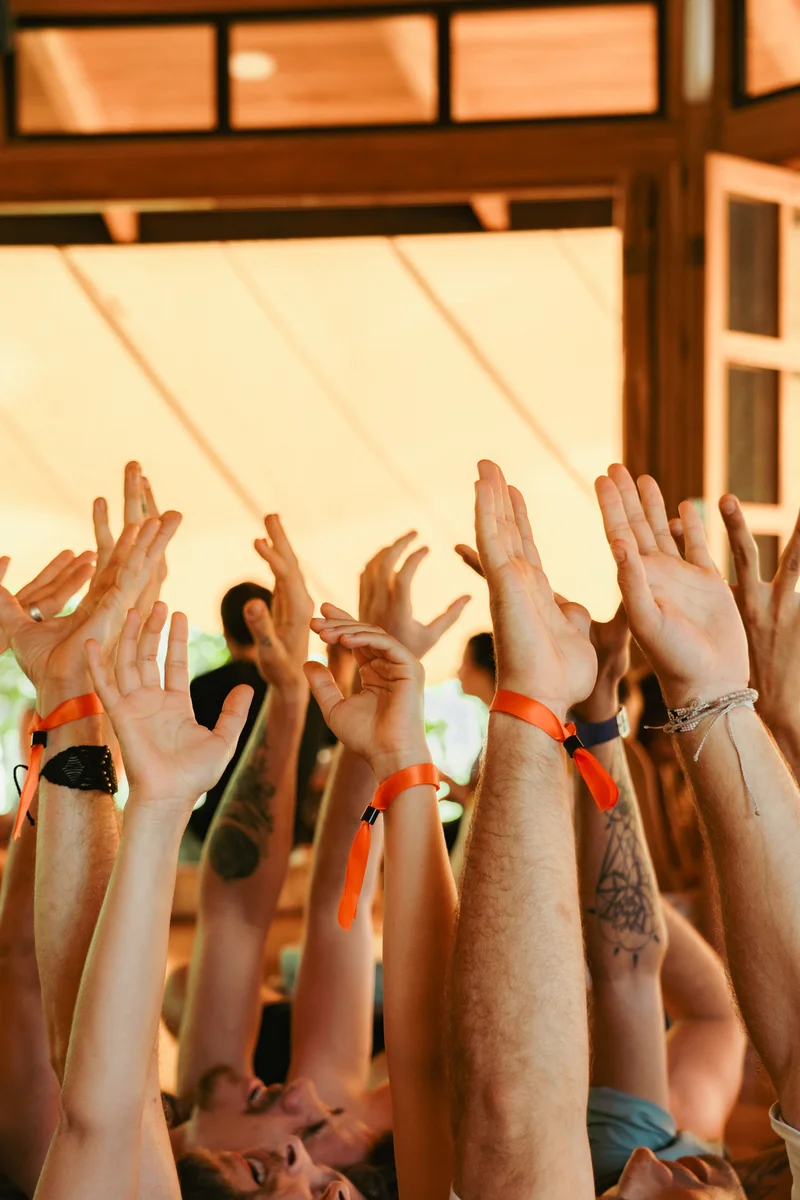 Hands raised together in the sunlit pavilion