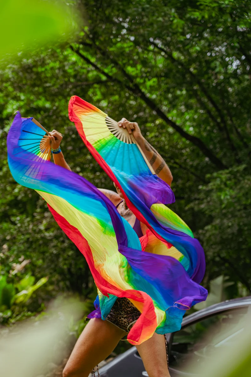 A dancer with rainbow silk fans in the jungle